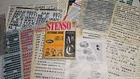 Photo displaying multiple vintage Stenso and Letraset lettering sheets and Stenso Lettering Guide booklet amidst sheets of transfer lettering.