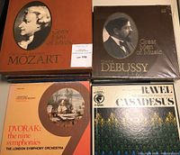Four vinyl LP albums from classical music collections including Great Men of Music series (Mozart, Debussy), Dvorak's nine symphonies, and Ravel's complete piano music.