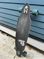 Top side showing black grip tape with white Sector 9 logo and green wheels, used condition with some dust.