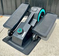 Front and top view of black Cubii Compact elliptical showing foot pedals, resistance knob, and base.