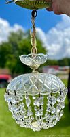 Close-up showing the top scalloped glass and metal chain hanging mechanism with clear sky background