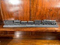 Full side view of the HO scale coal train model on its display base against a wooden background