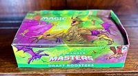 Closed box of Magic the Gathering Commander Masters Draft Boosters showing colorful artwork with a dragon and bats.