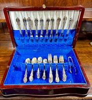 Front view of the tarnish-resistant chest open showing the flatware including knives in slots at top and spoons, forks, and tongs below in slots.