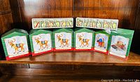 Four boxed Hallmark Keepsake Ready Reindeer ornaments in original green and red boxes alongside two trays of six painted glass balls each, totaling twelve balls.