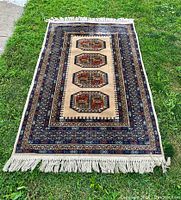 Full view of the rug laid out on grass showing complete pattern and fringe