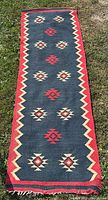 Full view of the vintage South Western indigenous style wool runner rug laid out on grass showing rectangular shape, color, and geometric motifs.