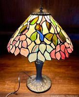 Front view of lamp lit, showing stained glass shade and base silhouette