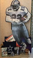 Cardboard cutout of Emmitt Smith holding a football, with football plate and books underneath.
