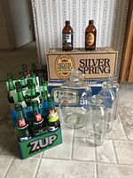 Assorted bottles and glass jugs with a box of Silver Spring bottles in the background.