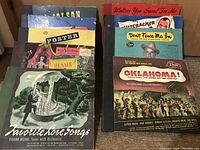 Photo showing assortment of vintage vinyl record covers arranged on a surface. Visible records include titles such as Oklahoma!, Favorite Love Songs by Frank Munn, Dennis Day, Bing Crosby, Al Jolson, and others from the 1910s and 1940s era.