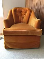 Front view of vintage gold velour bucket chair showing its plush cushioned arms, tufted backrest, and skirted base.