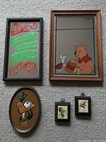 Photo of five juvenile-themed wall hangings and mirrors including the Homework Causes Pimples mirror, Winnie the Pooh mirror, Pluto wall hanging, and two small framed cartoon prints.