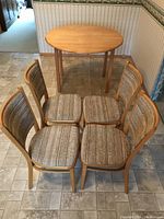 Overview photo showing the round pine kitchen table and four matching dining chairs with upholstered seats arranged in a square formation.