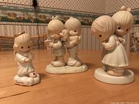 Three Precious Moments porcelain figurines on table, showing different poses and characters with puppies and children.