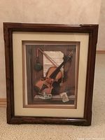 Front view of the shadow box frame containing paper tole artwork of a violin and other music-themed elements.