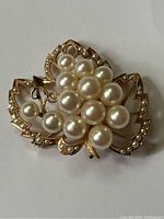 Front view of the gold brooch showing cluster of pearls and leaf design