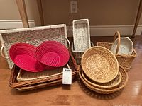 A group photo showing all baskets in the lot arranged together on the floor including large rectangular baskets, round baskets, and handled small baskets.