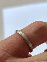 Ring on finger showing engraved scroll pattern and profile