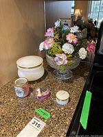 Overview of the lot showing the cut glass bowl with porcelain flowers, various small dishes including Limoges and frosted glass, and a decorative jar missing its lid