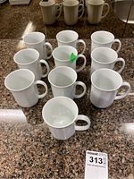 Ten white Fitz & Floyd Blanche Oblique mugs arranged on countertop, showing side and top views.