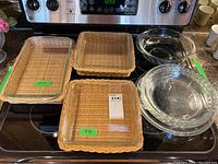 Wide shot showing arrangement of three Pyrex dishes and three woven wicker baskets on a stove top.