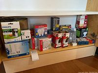 Shelf of assorted light bulb boxes including Sunbeam, Philips, Maxxled brands in different wattages and types.