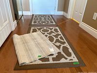 Two matching floor mats on the floor, with the small striped bath mat laid on top of one to show size comparison and design.
