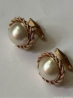 Pair of gold cufflinks displayed side by side on neutral background.