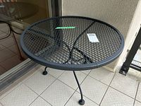 Metal patio side table showing top view and mesh pattern with three legs
