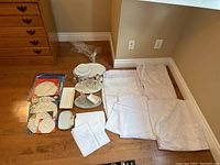 Full lot overview showing linens, ceramics, glassware, and plates arranged on floor