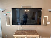 Front view of the wall-mounted TV above a cabinet, showing overall condition and screen size.