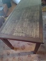 Rectangular wooden dining table with bamboo inlay under a glass top, shown in room with furniture and carpet