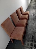 Front angled view of four brown upholstered Parsons chairs in a row, showing seats and backrests.