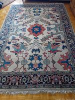 Top-down view showing full rug with central red and blue medallion and multi-colored floral patterns on cream background.