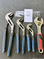 Full view of all four wrenches including three blue-handled Kobalt channel lock pliers and one red and black adjustable wrench.