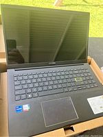 Front view of Asus VivoBook 15 laptop showing full keyboard, touchpad, and cracked screen.