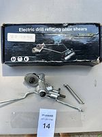 Photo showing the electric drill refitting plate shears metal tool parts laid out in front of the original black box with white labeling.