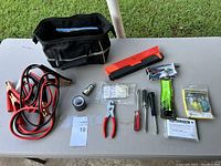 Full kit contents including all tools, cables, and bag laid out on table against outdoor grassy background.