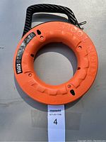 Top view of the orange Klein Tools fish tape reel showing the black handle and embossed Klein Tools branding.