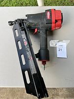 Full view of Ryobi large framing nailer, black with red accents, placed on a light surface.