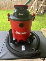 Front view of the Bauer 14 gallon wet dry shop vacuum with hose and attachments displayed on table.