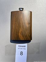 Front view of metal flask showing wood-grain textured exterior with screw-top lid.