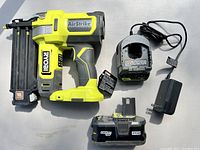 Ryobi AirStrike cordless nailer, battery charger and 4Ah battery laid out showing all items included in the lot.