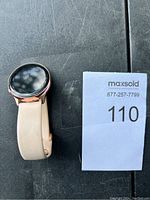 Front view of Samsung Galaxy smartwatch with round black display and rose gold bezel. Pink band attached.