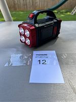 Photo showing front side with 4 round LED bulbs and handle with red power button.