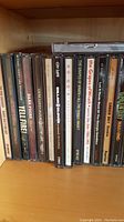 Shelf of music CDs including titles from The Grapes of Wrath, Green Day, Guns N' Roses, and others.