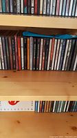 Photo of wooden shelves filled with multiple rows of music CDs showing the spines and part of the jewel cases.