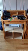 Front view of pine desk with items on top and two wooden boxes underneath.