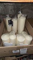 Photo showing a box with 8 white Ikea Fenomen pillar candles sealed in plastic.